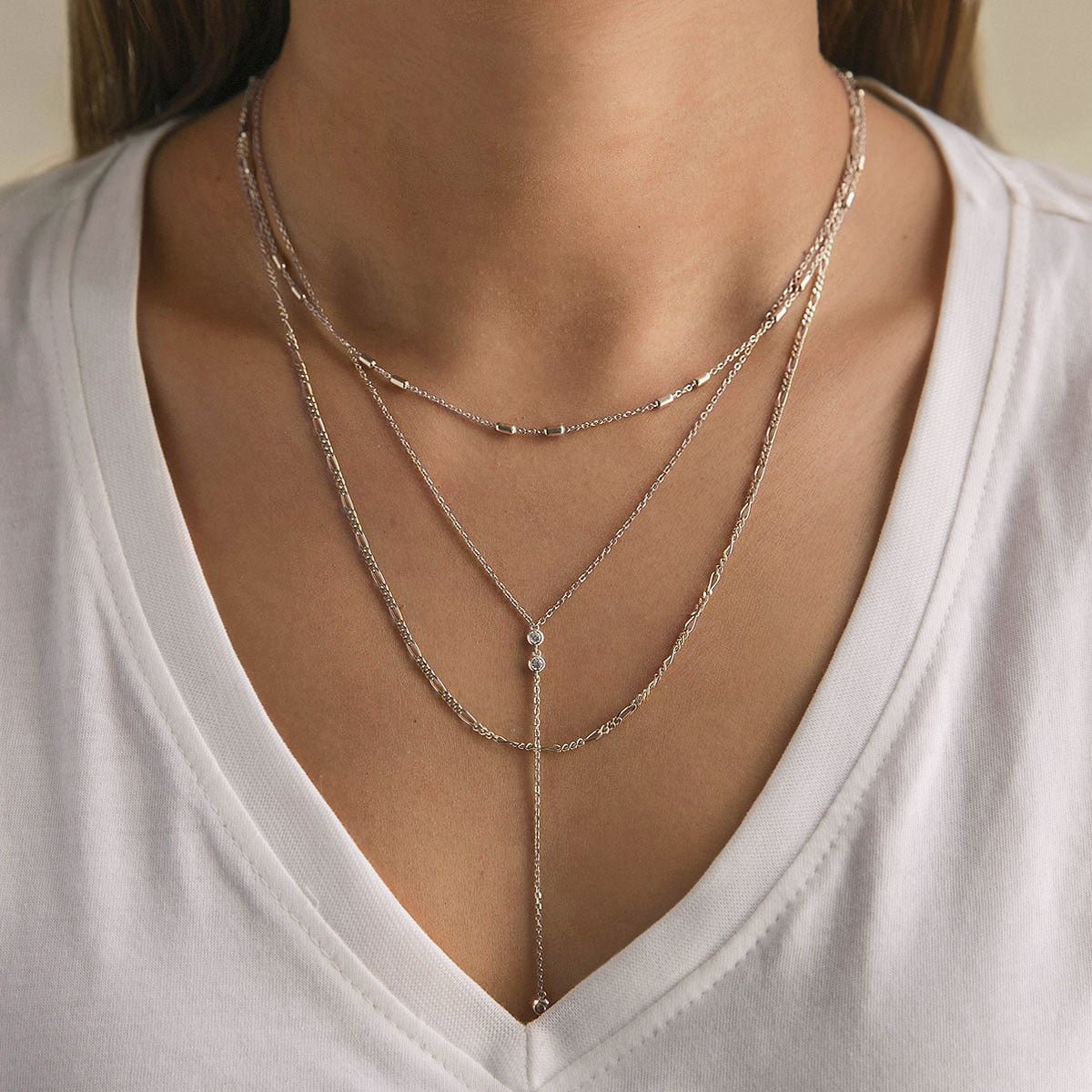 Sterling silver Figaro chain necklace layered with a clear-stone lariat chain, shown on a model