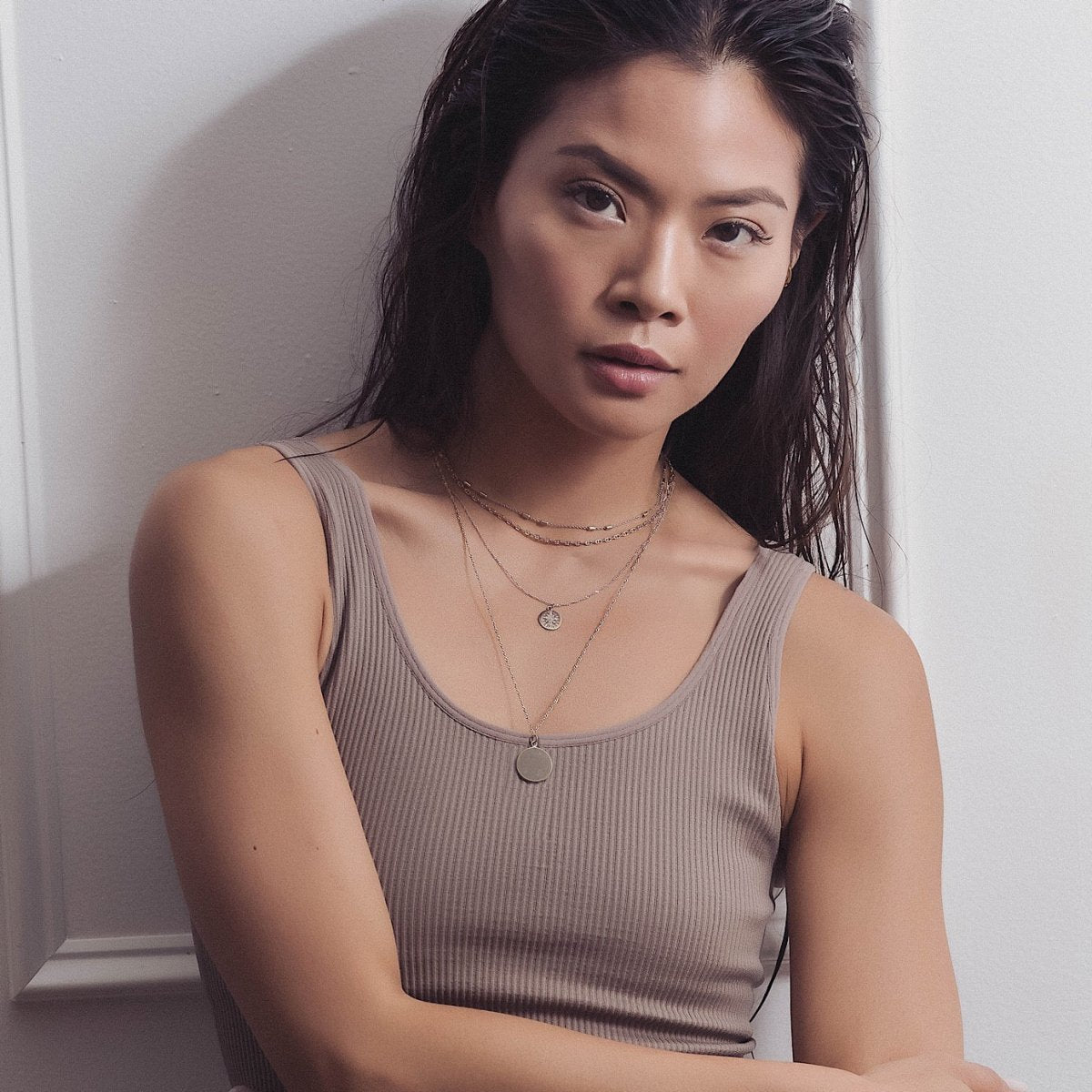 Sterling silver round disc pendant necklace layered with chains, shown on a model's neckline