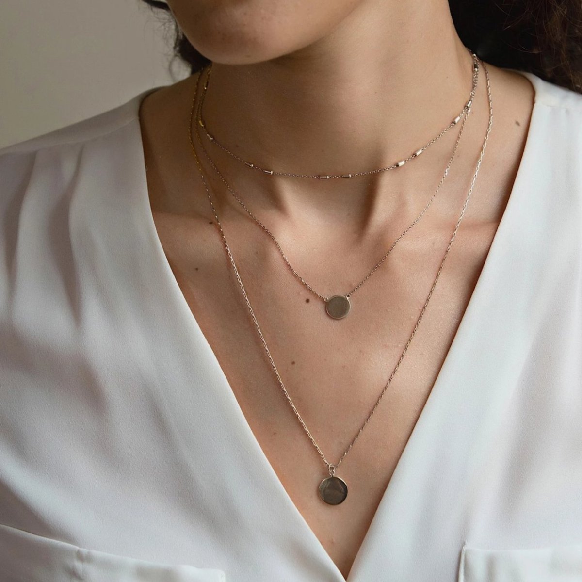 Sterling silver layered choker and two disc pendant necklaces, shown on a model's neckline