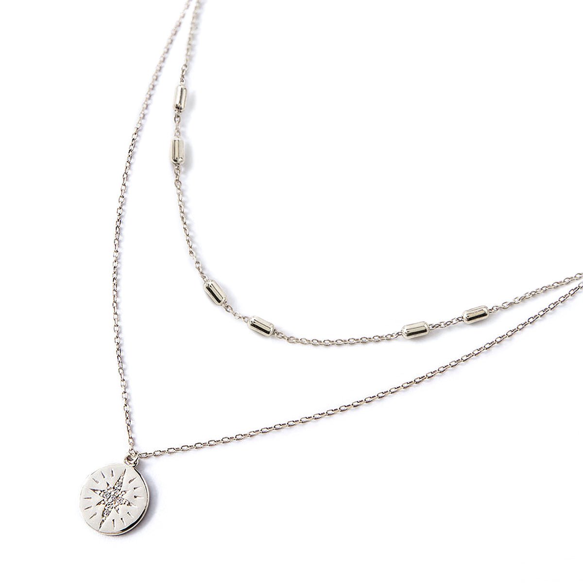 Sterling silver layered necklace duo with a starburst disc pendant set with a clear stone, on a white background