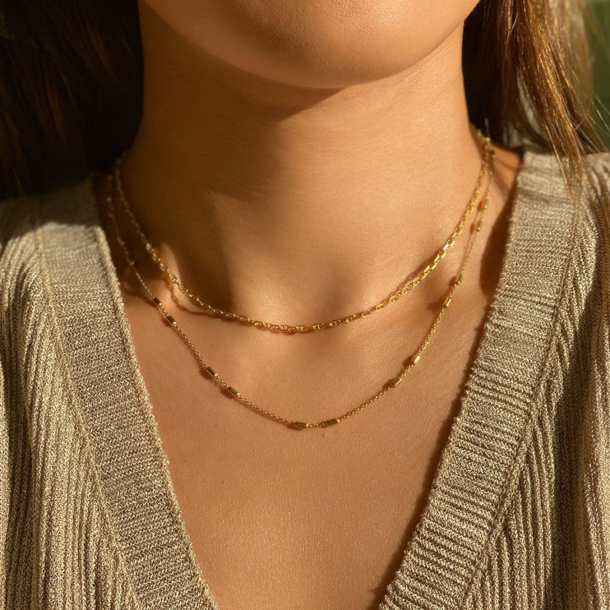Gold vermeil layered choker duo shown close on a model's neckline in sunlight