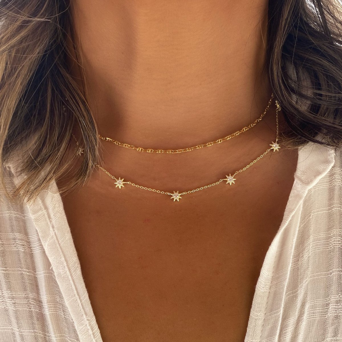 Gold vermeil layered Marina and white zirconia starburst necklaces, shown close on a model's neck