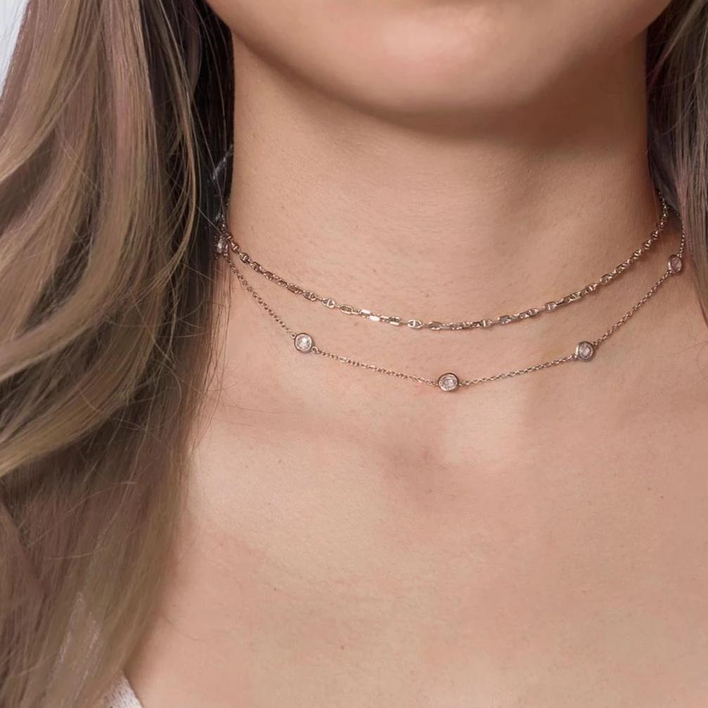 Sterling silver Marina chain layered with a clear crystal station chain, shown on a model's neckline
