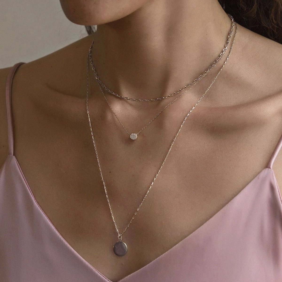 Sterling silver Marina chain, crystal disc and round disc pendant layered trio, shown on a model's neckline