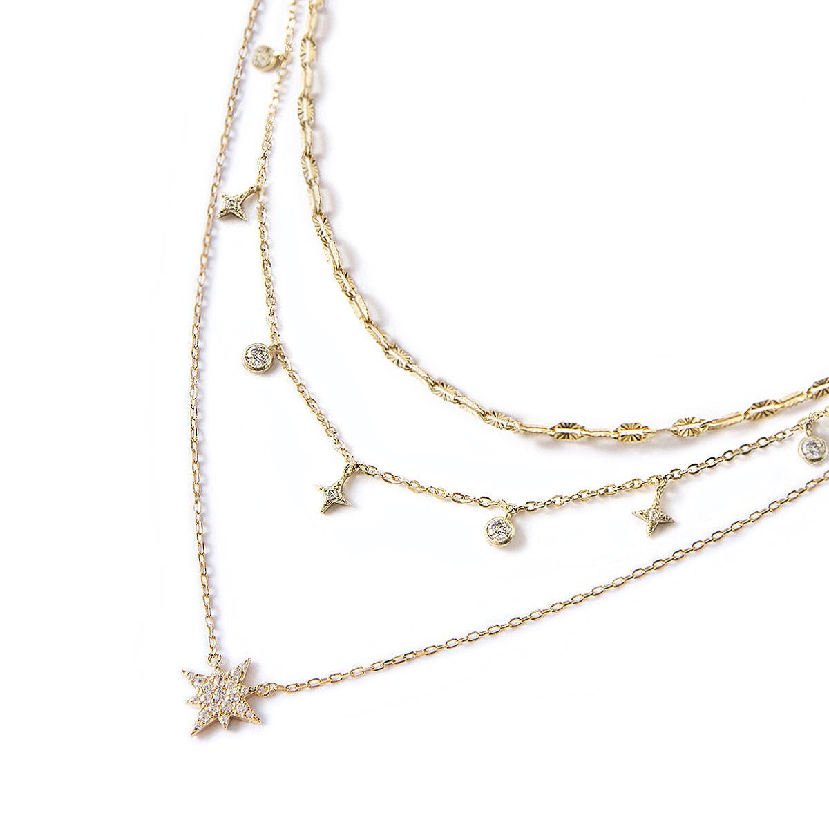 Gold vermeil layered trio necklace with a starburst pendant and dangling clear zirconia, on a white background