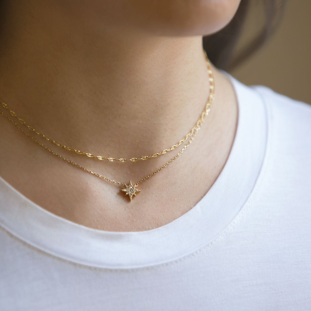 Gold vermeil layered duo of a lace chain and a pavé star pendant chain, shown on a model's neckline