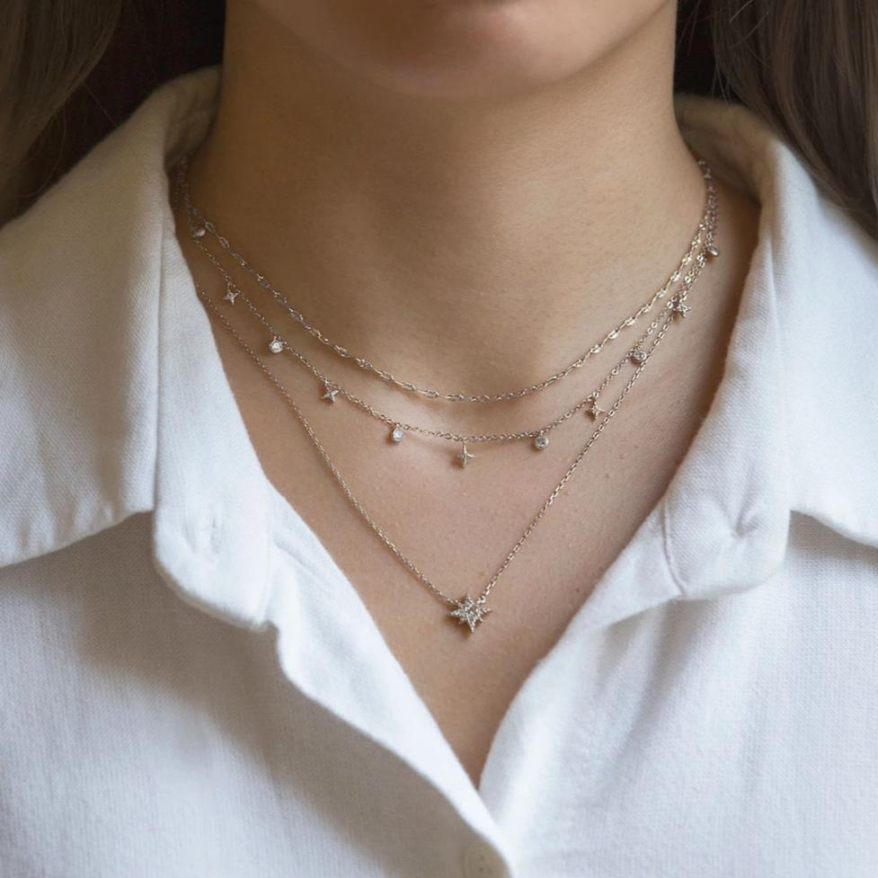 Sterling silver layered trio of star and zirconia drop chains with a pavé star pendant, shown on a model's neckline