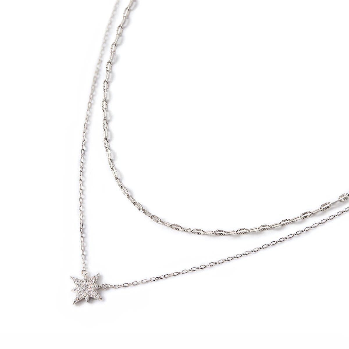 Sterling silver layered duo of a textured lace chain and a pavé star pendant chain, on a white background