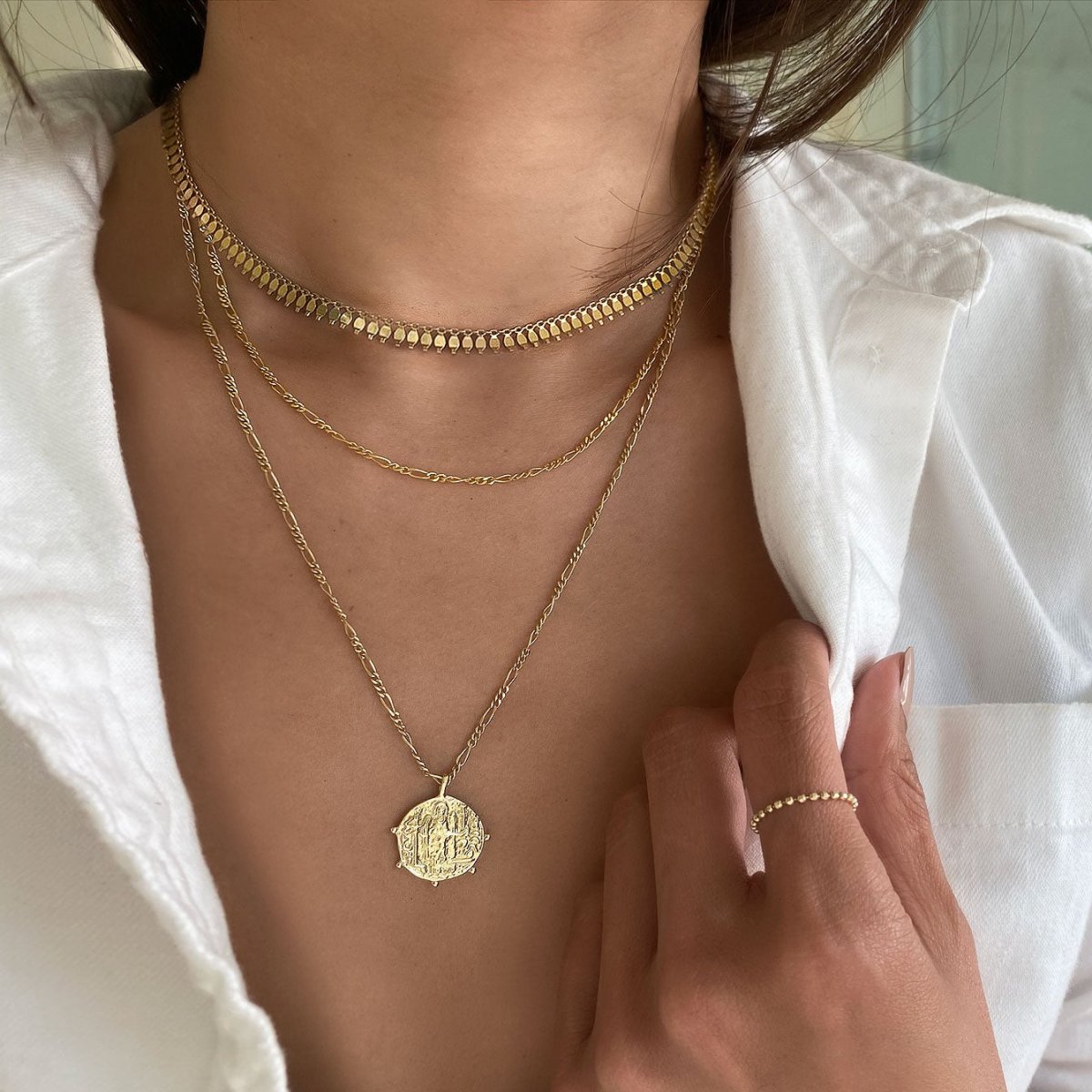 Gold vermeil Figaro chain necklace layered with a beaded choker and coin pendant, on a model