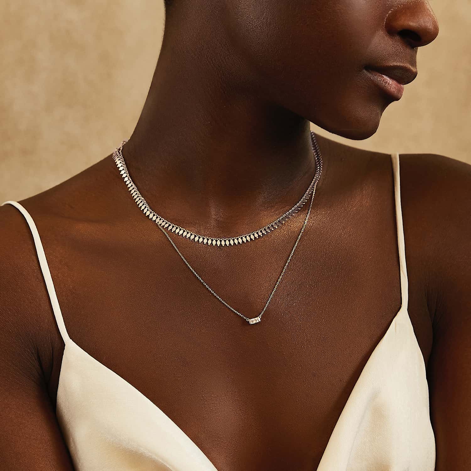 Sterling silver fringe chain necklace with a small baguette clear stone pendant, shown on a model's neck