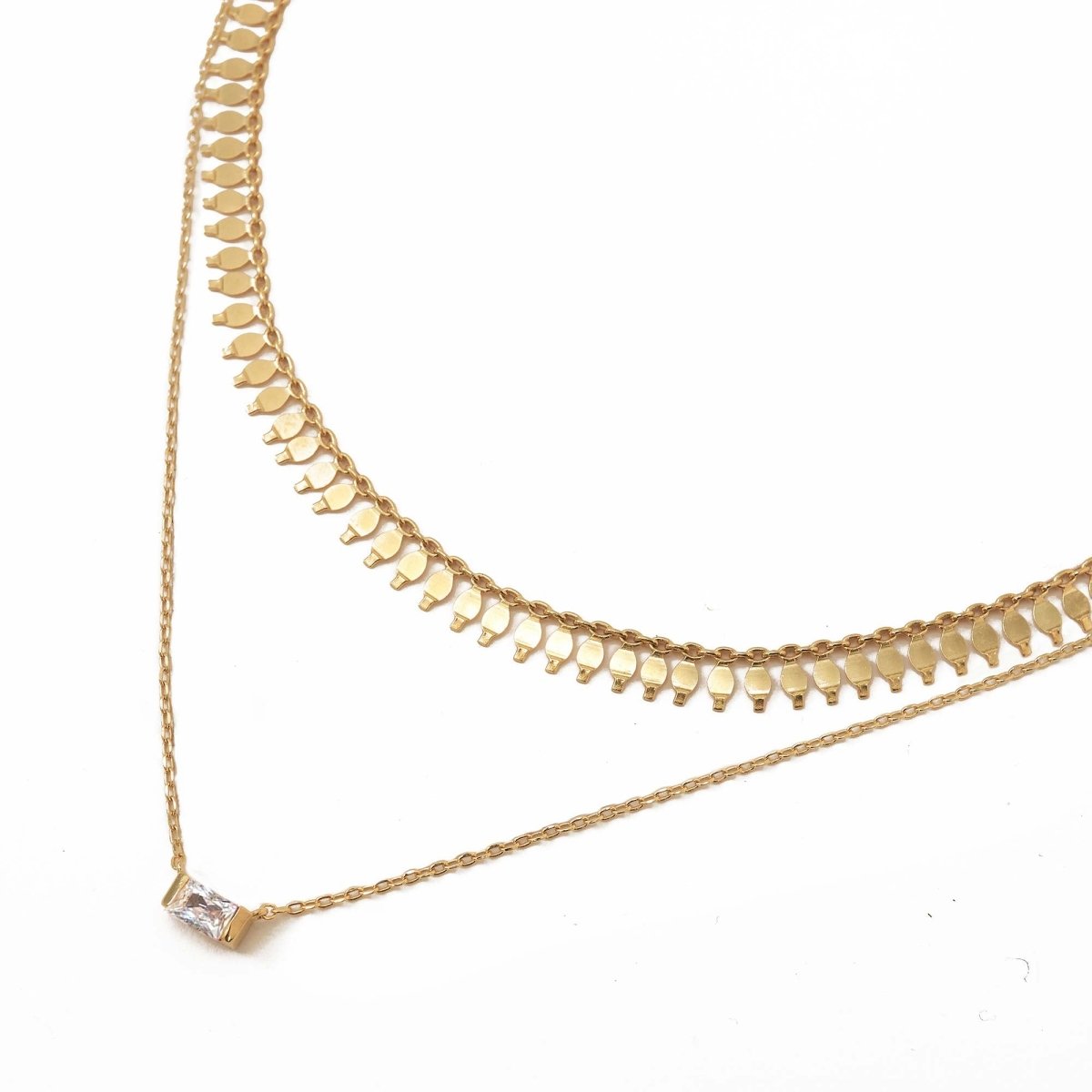 Gold vermeil layered duo with a clear baguette stone pendant, on a white background