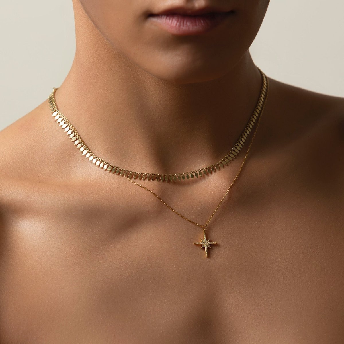 Gold vermeil starburst pendant with clear stones, layered with a chain choker on a model's neckline