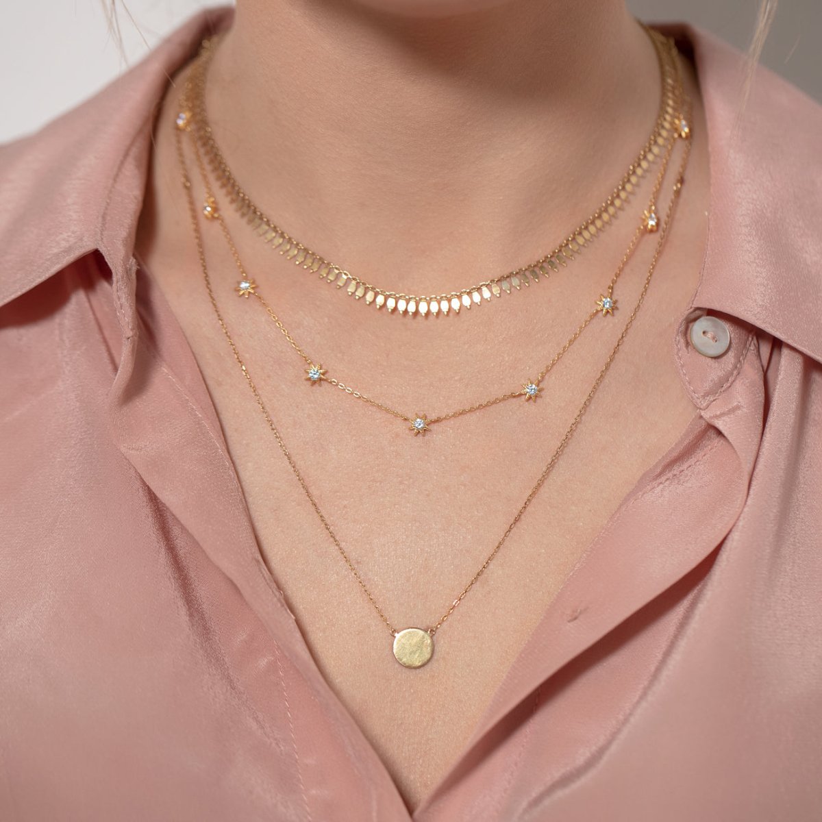 Gold vermeil fringe chain choker layered with star and disc pendant chains, shown on a model's neckline
