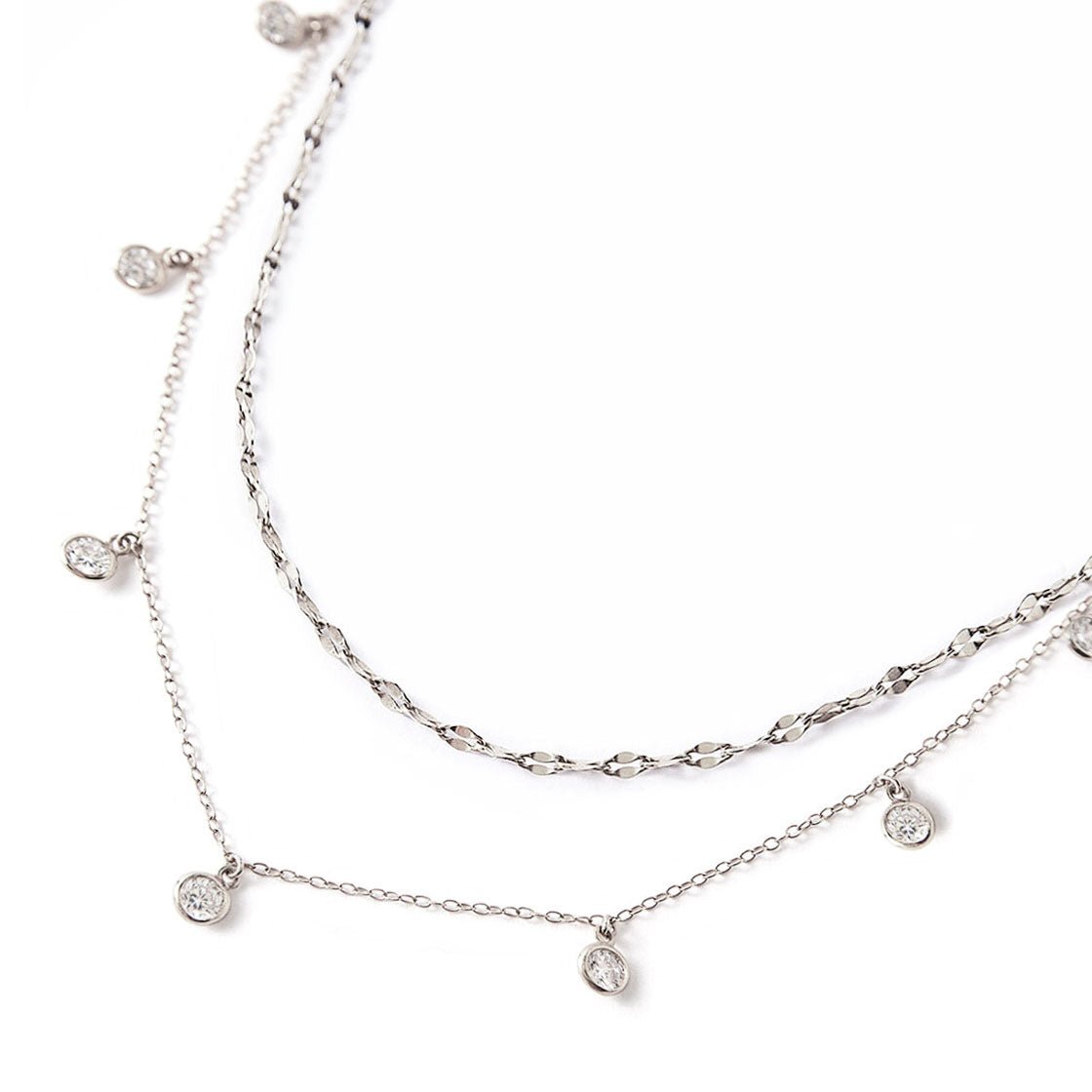 Sterling silver layered necklace duo with a textured chain and dangling round clear stones, close-up detail