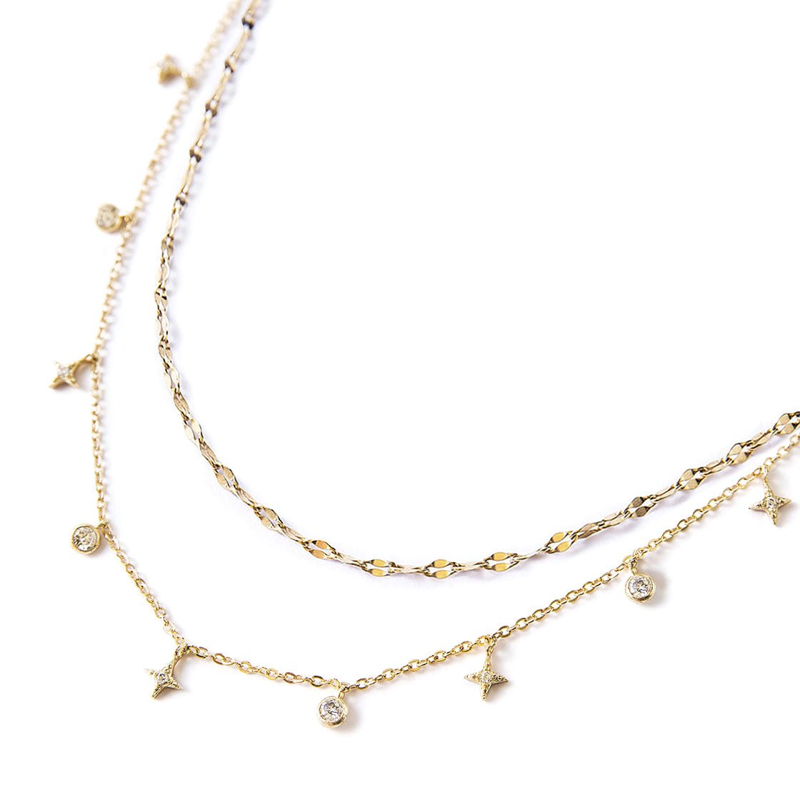 Gold vermeil layered necklace duo with dangling star and round clear stone charms, on a white background