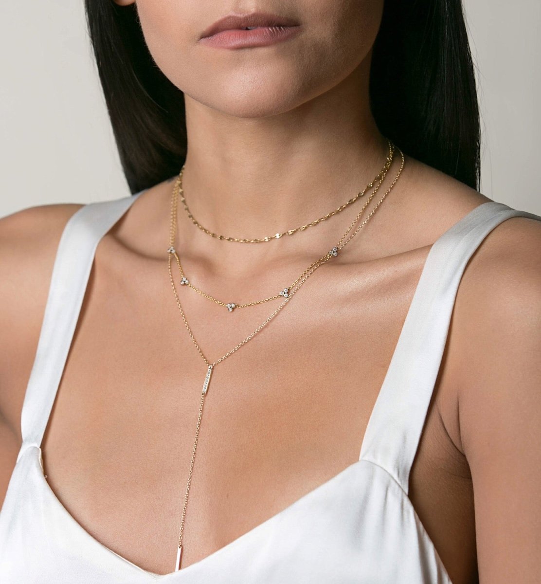 Gold vermeil clover bar lariat layered duo with a drop bar, shown on a model's neckline