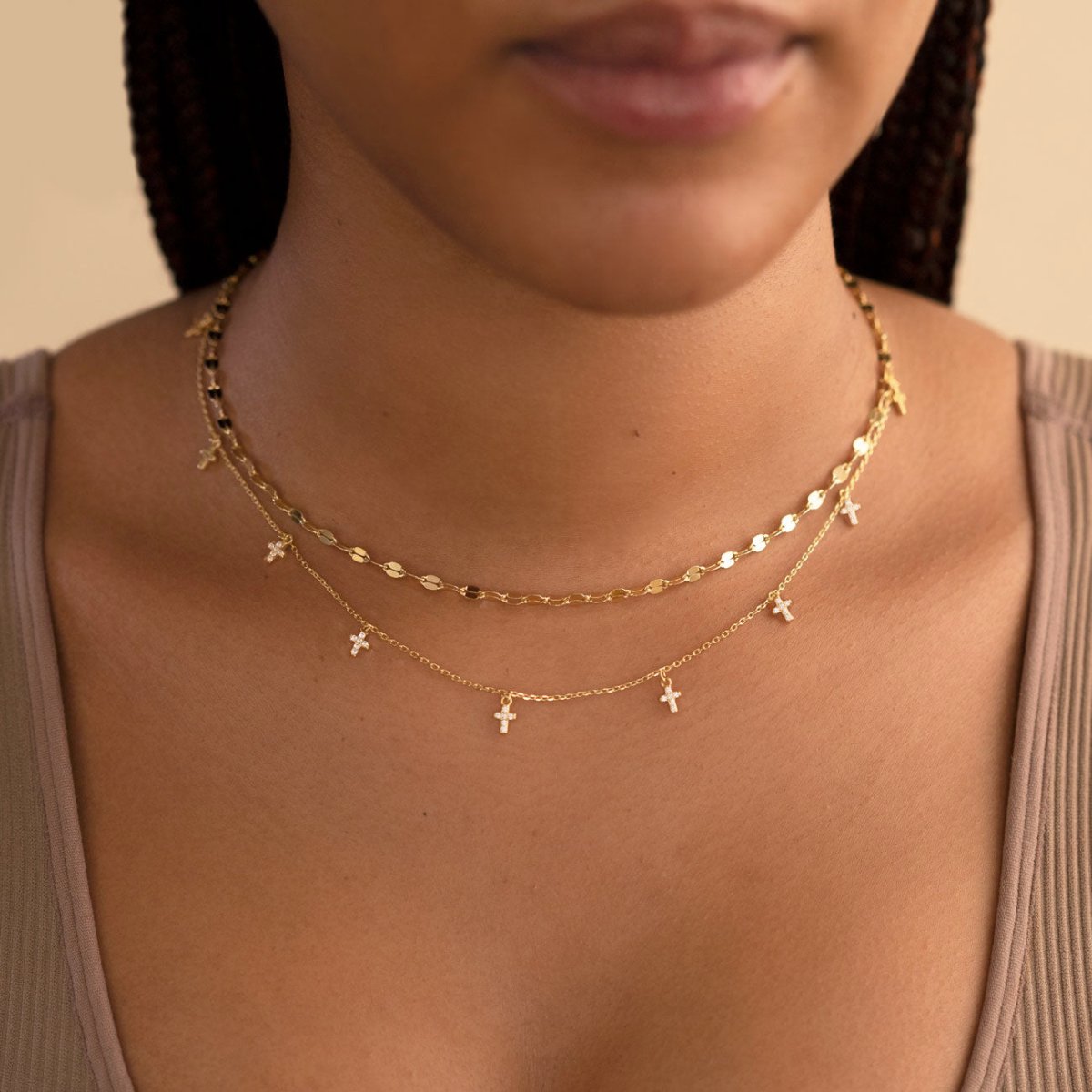 Gold vermeil mirror-link chain layered with a zirconia cross-charm chain, shown on a model's neckline