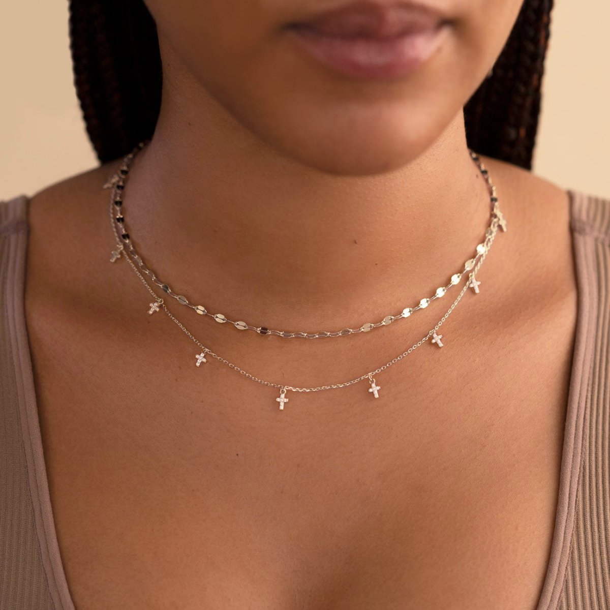 Sterling silver white zirconia cross dangle necklace layered on a model's neckline