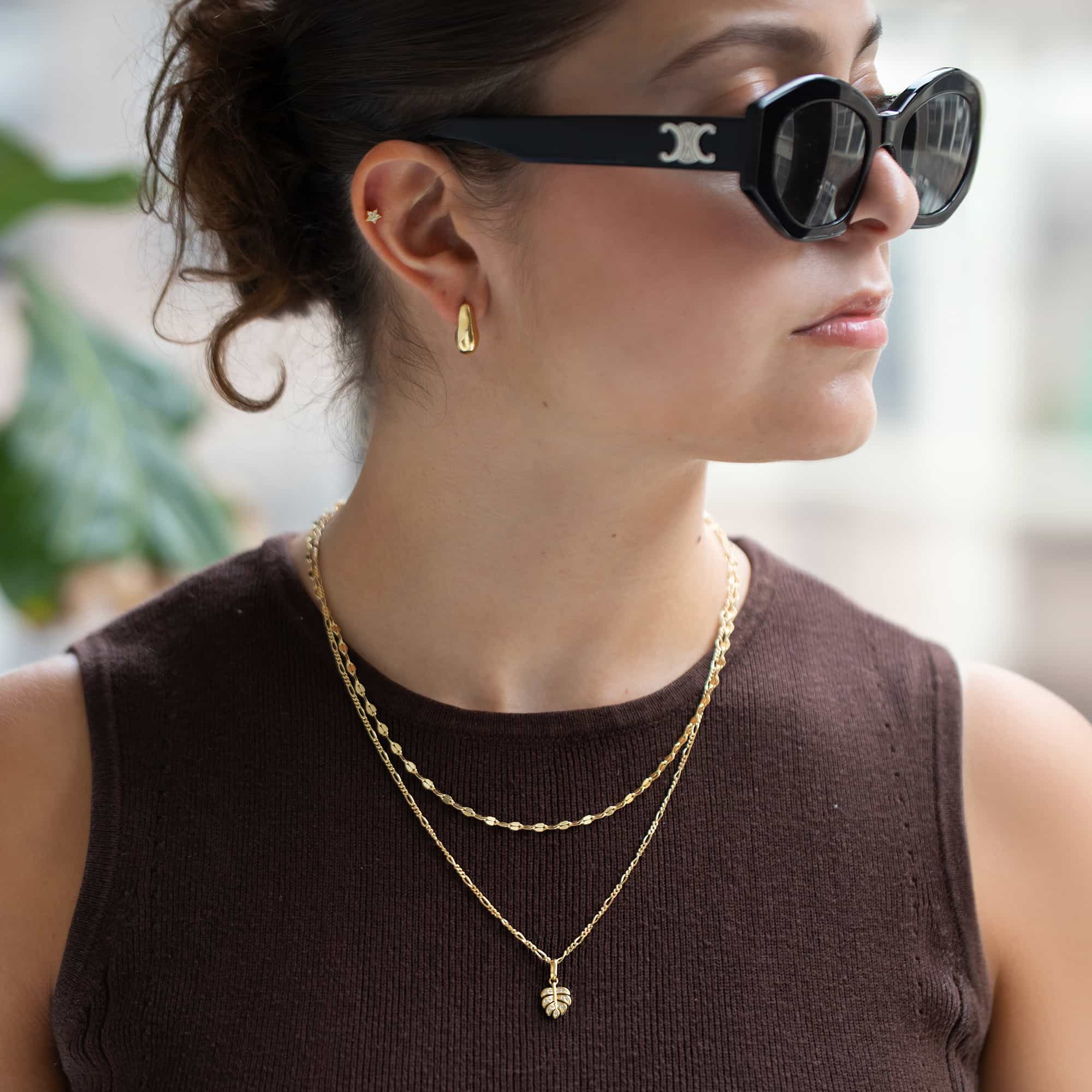 Gold vermeil monstera leaf pendant on a layered chain necklace, shown on a model