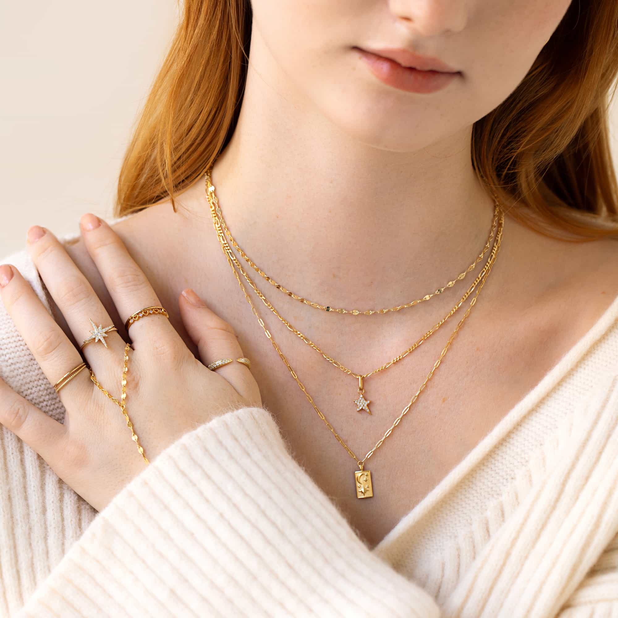 Gold vermeil pavé star pendant with clear stones on a layered necklace, shown on a model's neckline