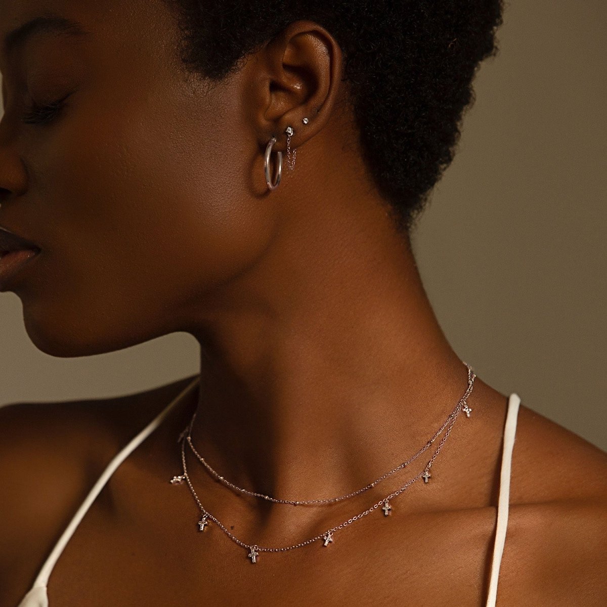 Sterling silver beaded chain choker on a model's neckline with small dangling clear-stone charms