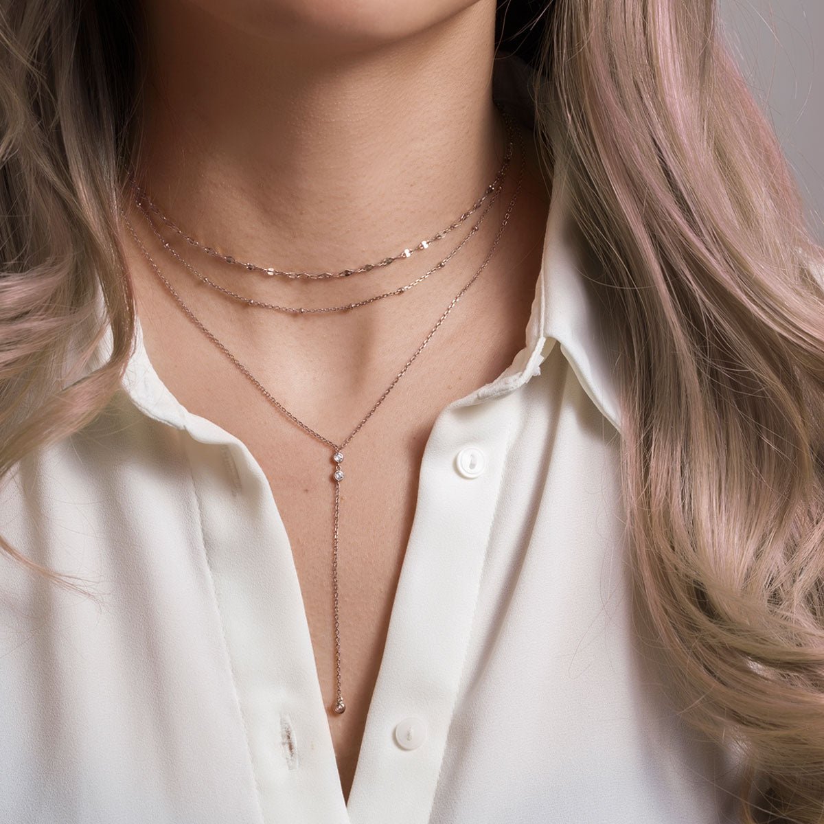 Sterling silver zirconia lariat necklace layered with two chains, shown on a model's neckline