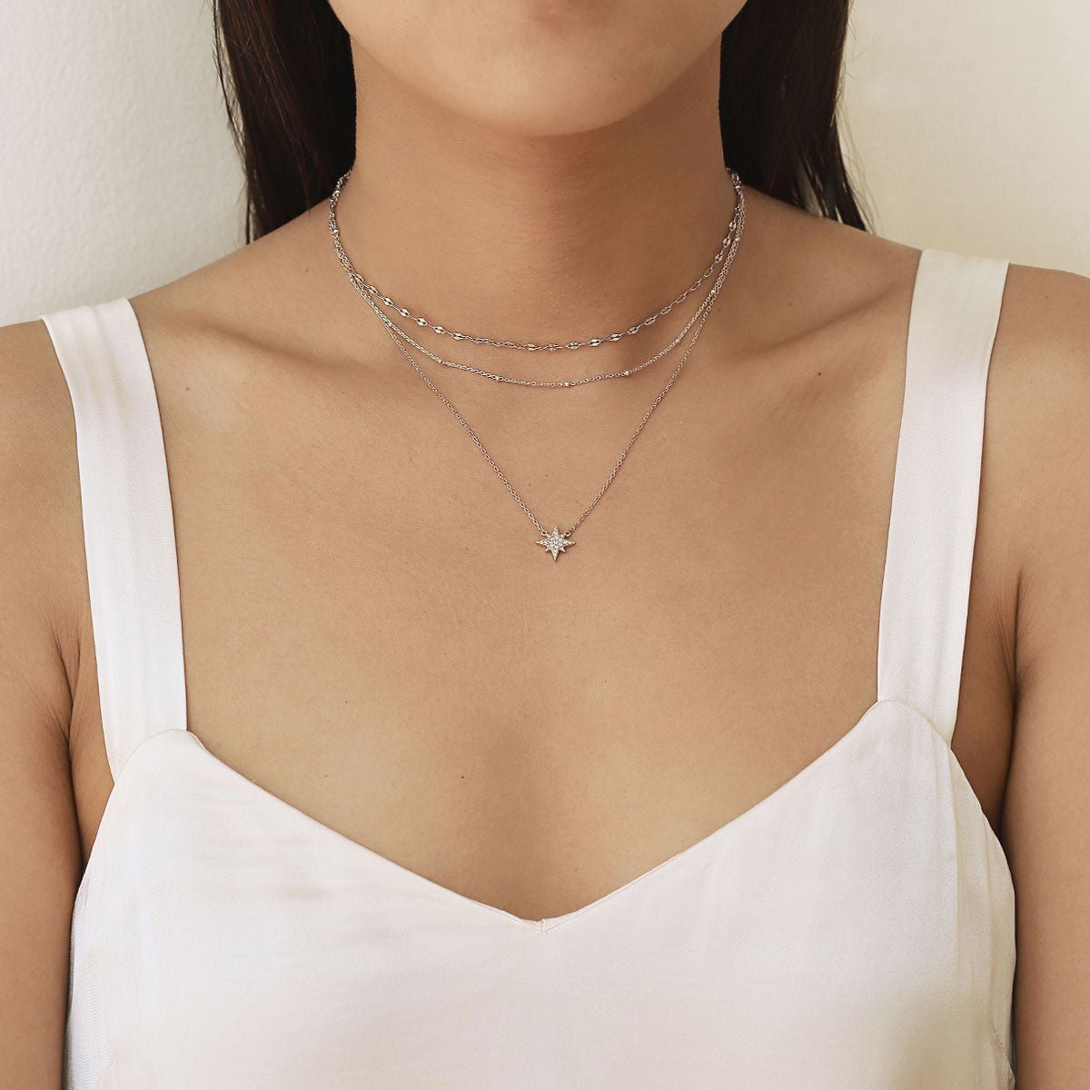 Sterling silver starburst pendant necklace with white zirconia pave, layered and shown on a model's neck