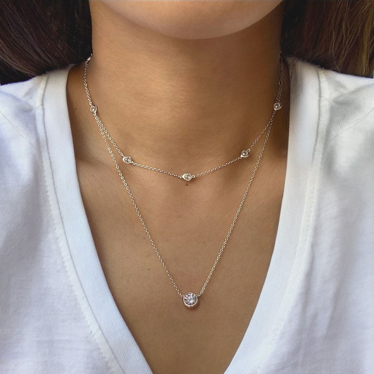 Sterling silver layered station choker and clear solitaire pendant, shown on a model's neckline