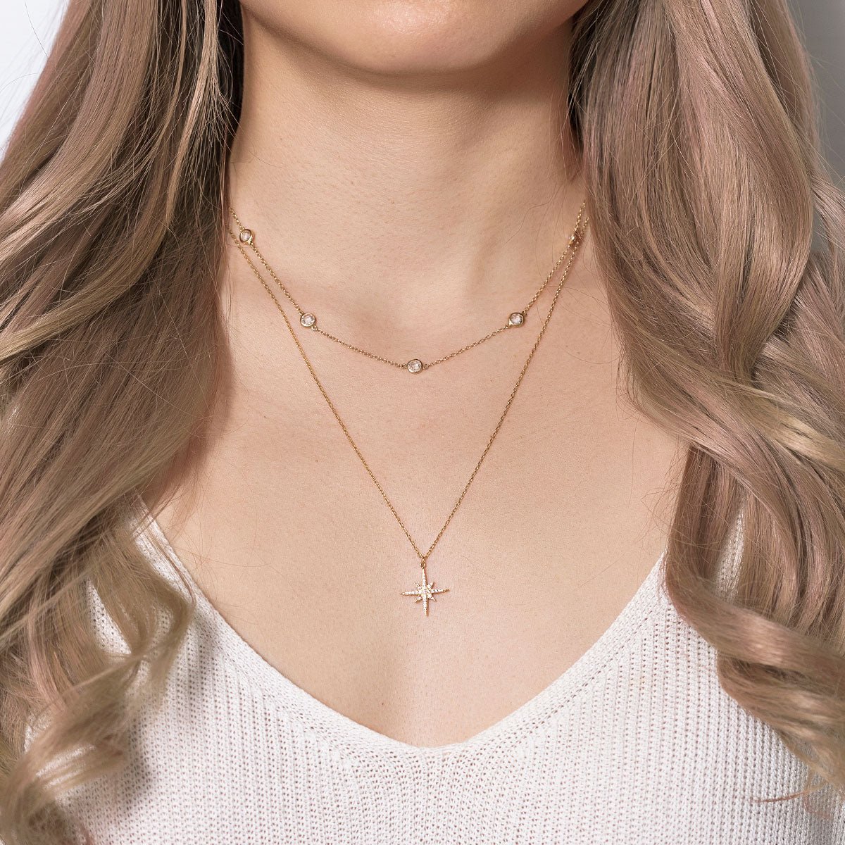 Gold vermeil layered star-pendant necklace duo with clear stones, shown on a model's neckline