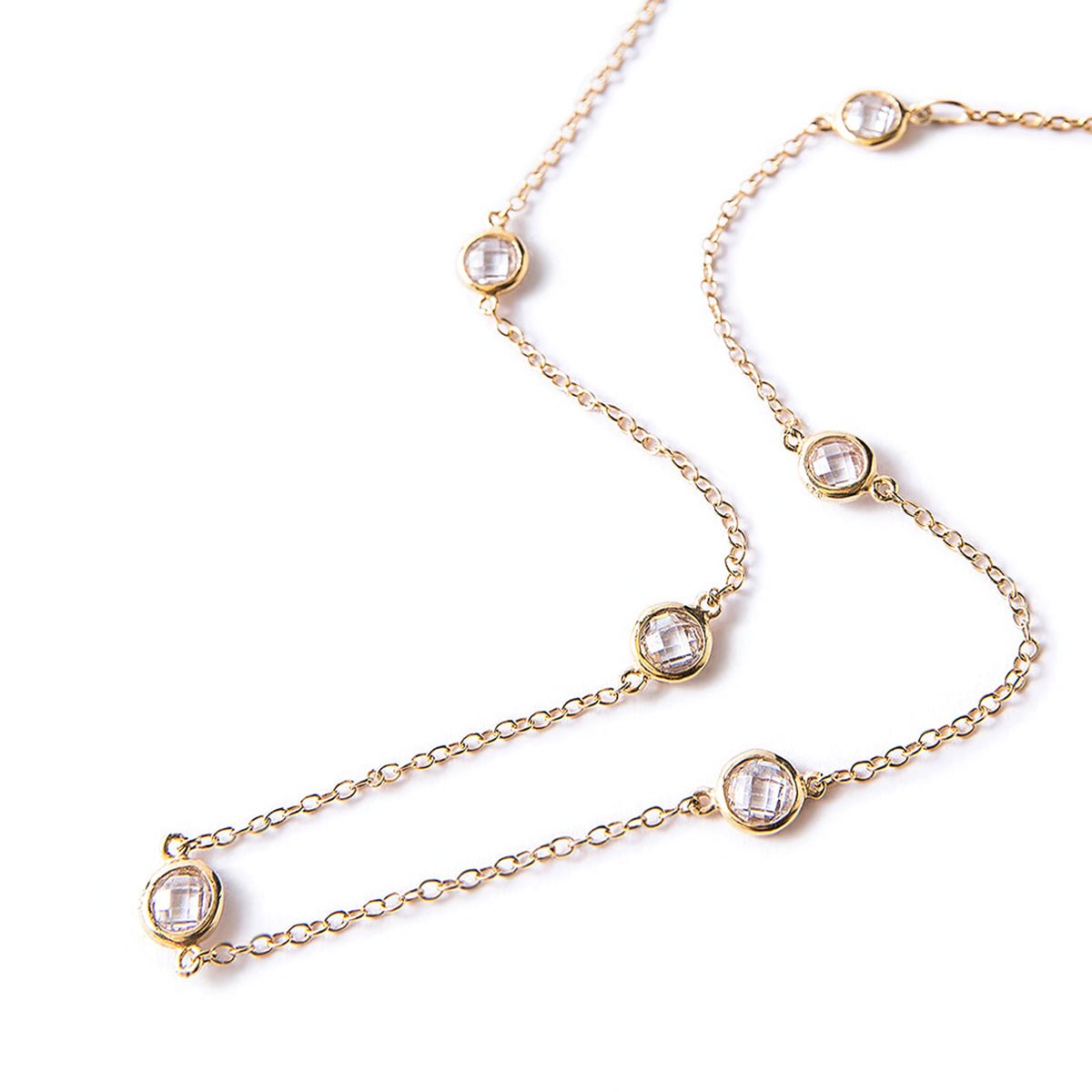 Gold vermeil station choker with round clear faceted stones along the chain, laid on a white background