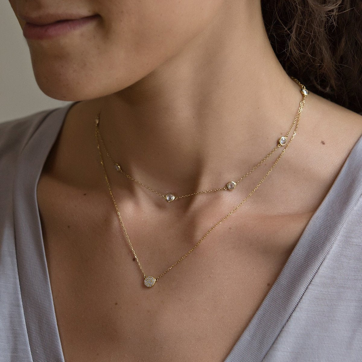 Gold vermeil pavé disc necklace layered with a white zirconia station chain on a model