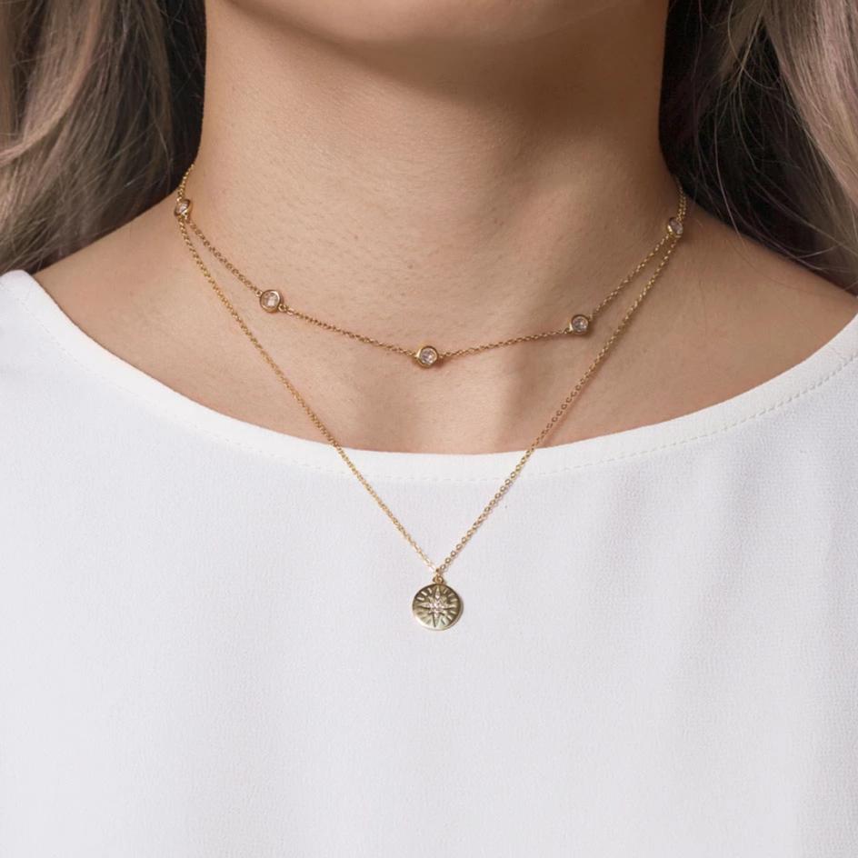 Gold vermeil layered station necklace and star disc pendant with white zirconia, on a model's neckline