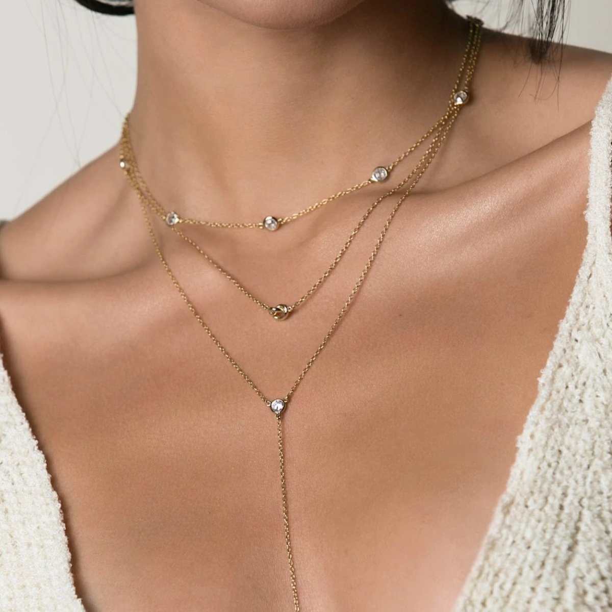 Gold vermeil zirconia lariat necklace layered as a trio, shown on a model's neckline
