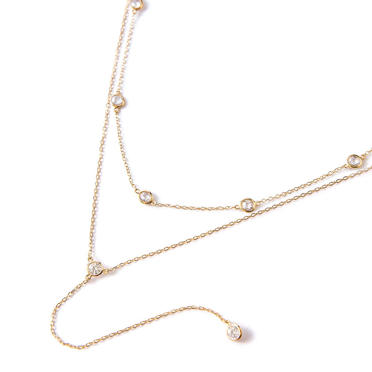 Gold vermeil layered station choker and white zirconia lariat necklace, laid on a white background