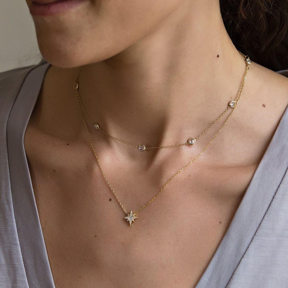 Gold vermeil starburst pendant necklace with white zirconia pave, layered and shown on a model's neck