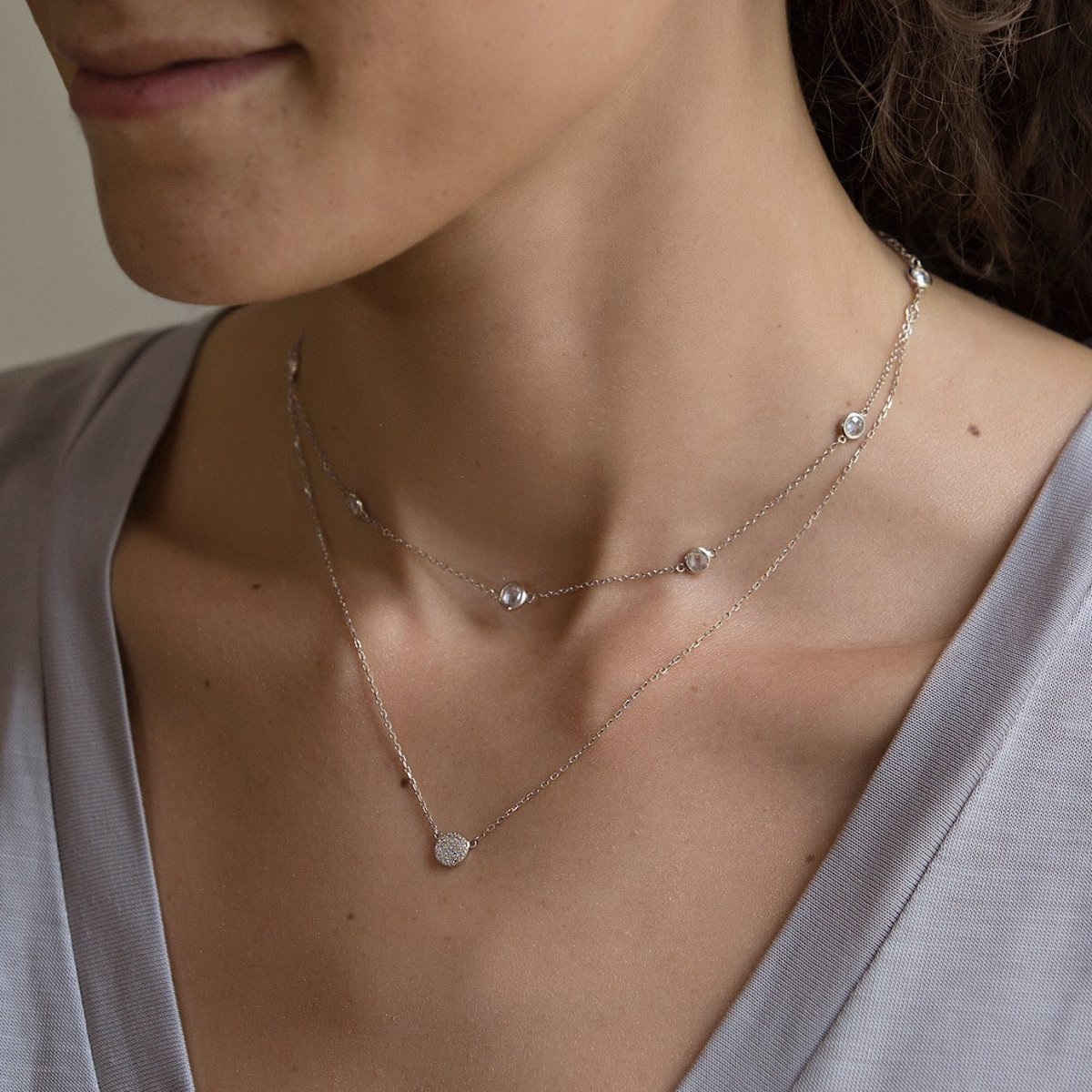 Sterling silver pavé disc necklace layered with a white zirconia station chain on a model