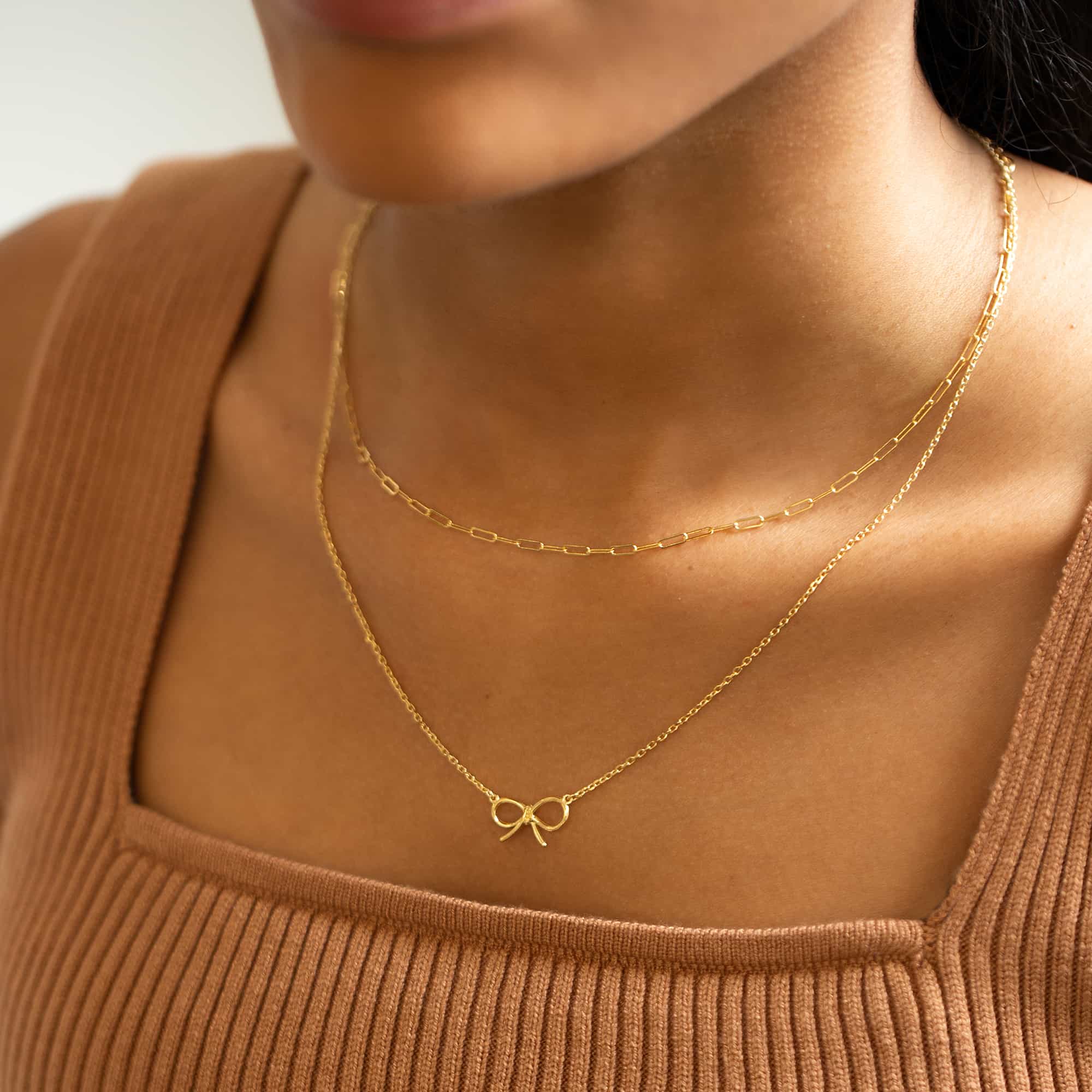 Gold-filled paperclip chain necklace layered with a finer chain, shown on a model's neckline