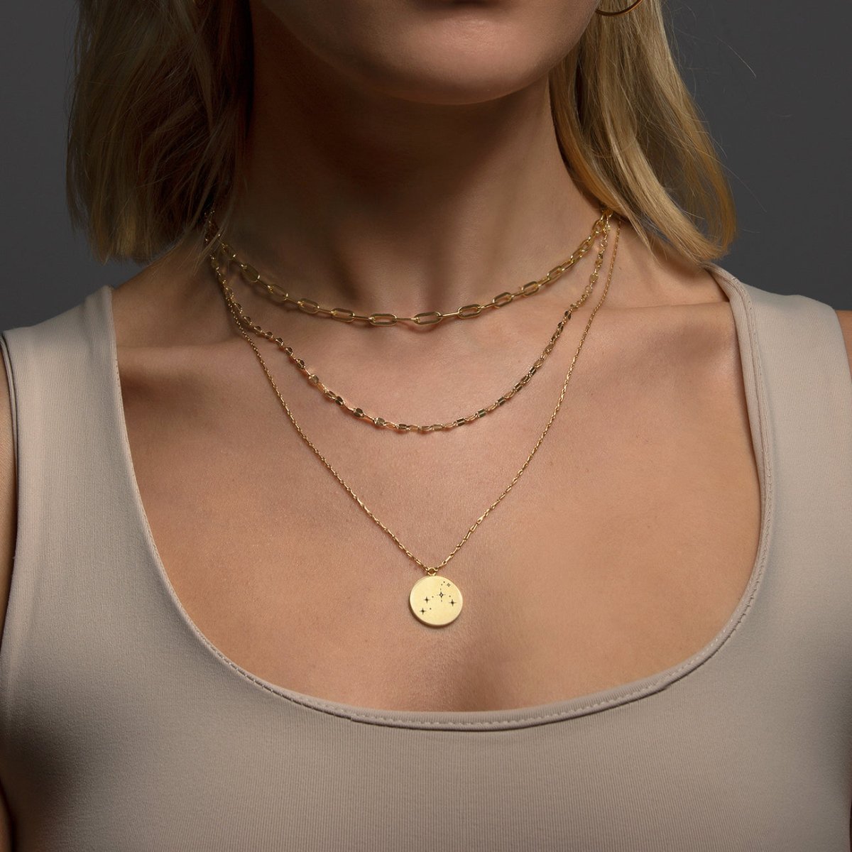 Gold vermeil round constellation disc necklace layered with chains, shown on a model's neckline