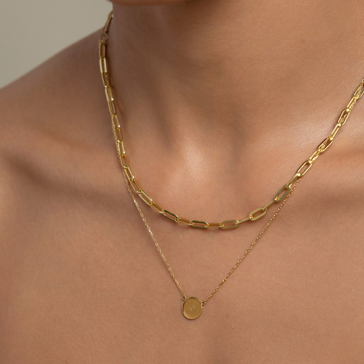 Gold vermeil petite zodiac disc pendant layered under a paperclip chain, shown on a model's neckline
