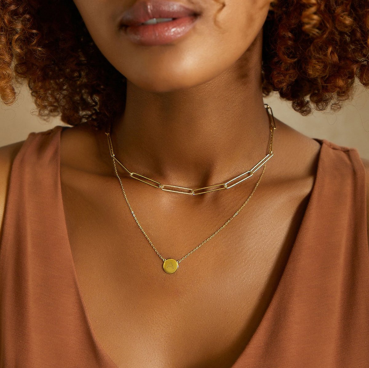 Gold vermeil disc necklace engraved with an initial, layered with a paperclip chain on a model's neckline