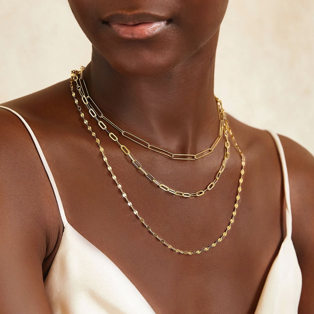 Gold vermeil mirror-link chain necklace layered with a paperclip and a fine chain, shown on a model's neckline