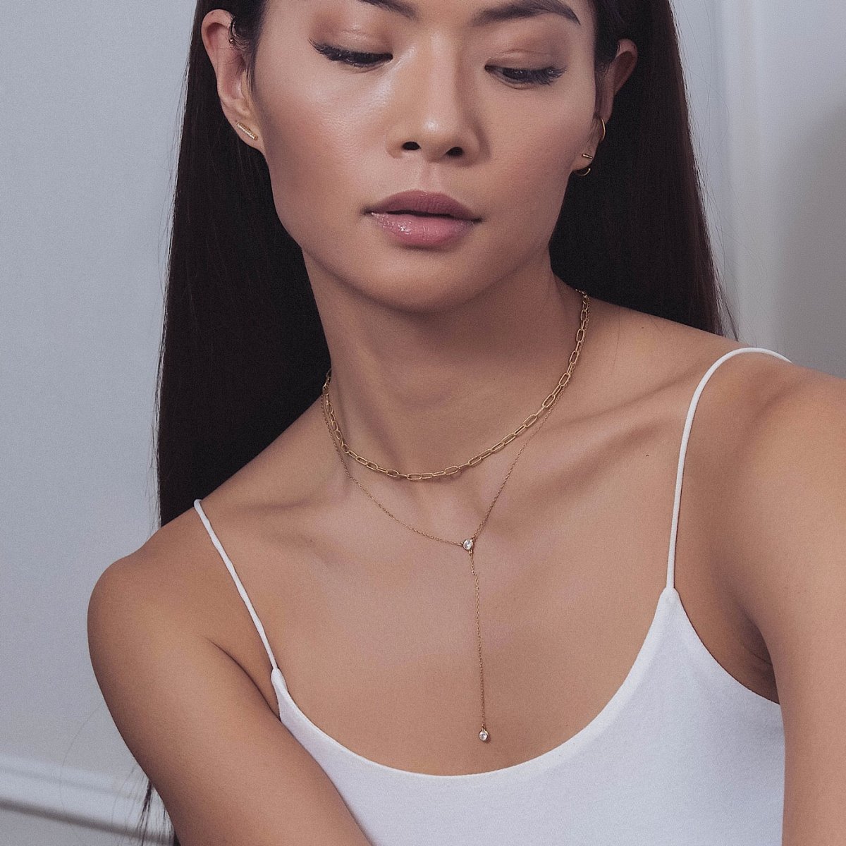 Gold vermeil zirconia lariat necklace layered with a paperclip chain, shown on a model's neckline