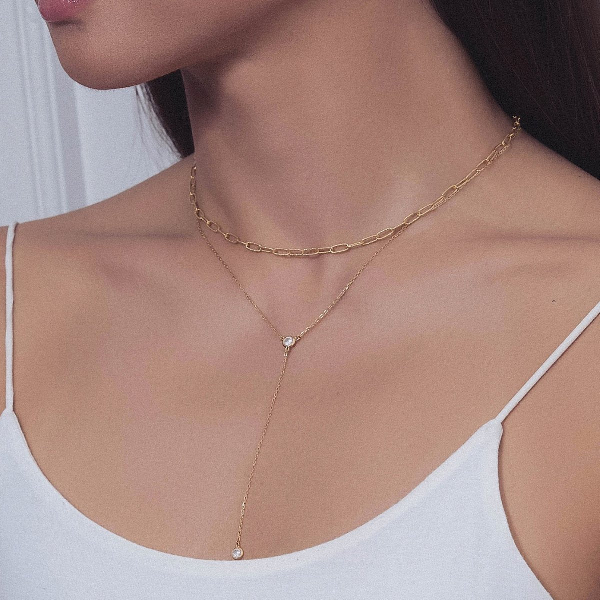 Gold vermeil lariat chain duo with a clear crystal drop, shown on a model's neckline