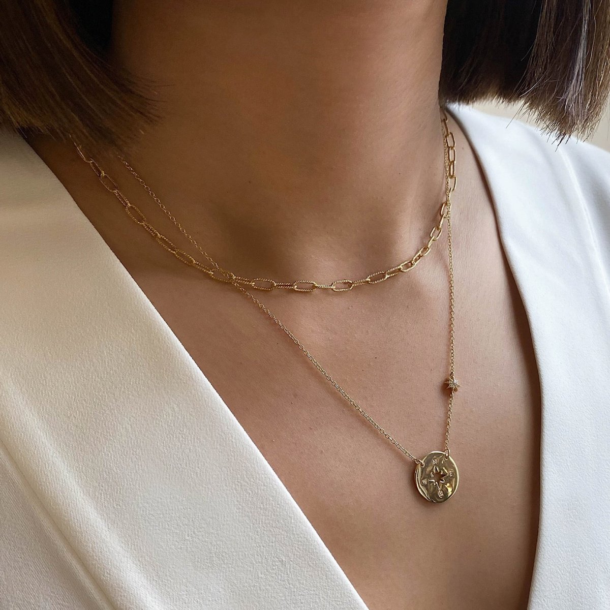 Gold vermeil compass disc necklace with a star station, layered on a model's neckline