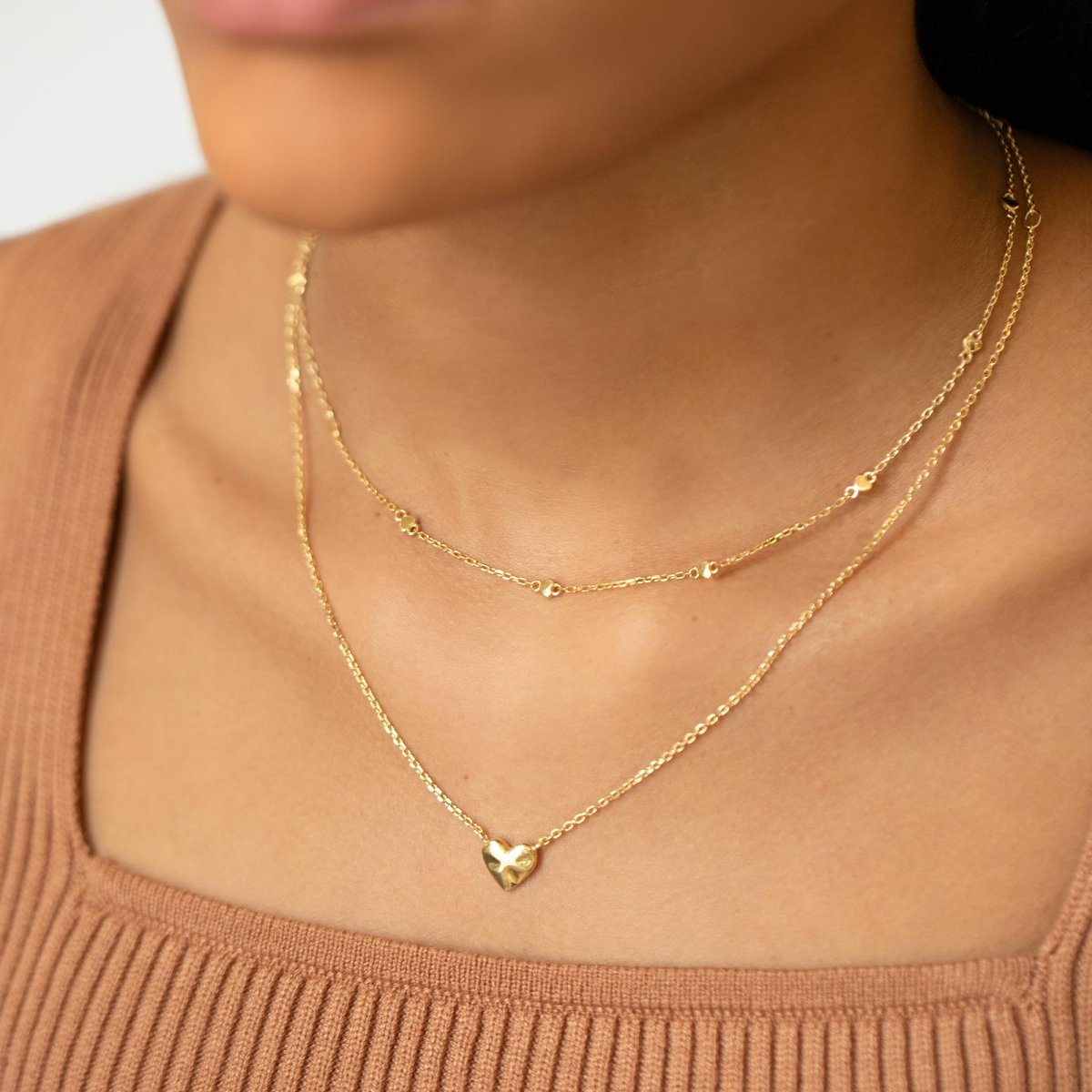 Gold vermeil heart-station chain layered with a gold heart pendant, shown on a model's neckline