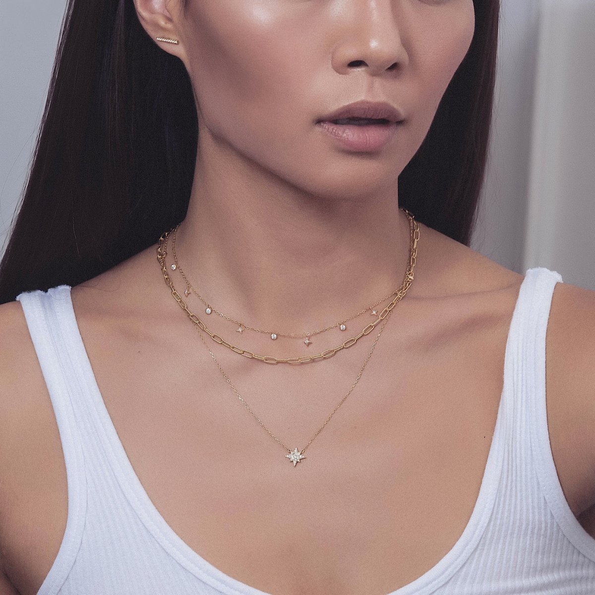 Gold vermeil starburst layered chain trio with clear crystal charms, shown on a model's neckline