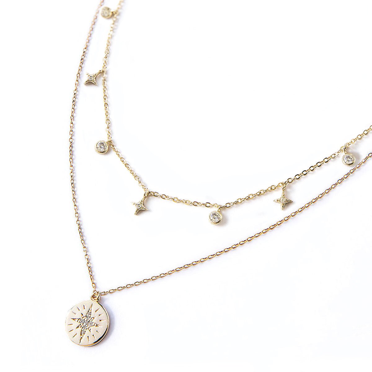 Gold vermeil layered duo with a starburst disc pendant and a star and clear stone station chain, on a white background