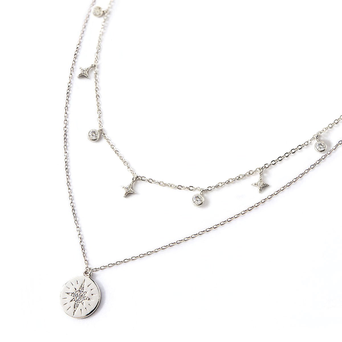 Sterling silver layered duo with a starburst disc pendant and a star and clear stone station chain, on a white background