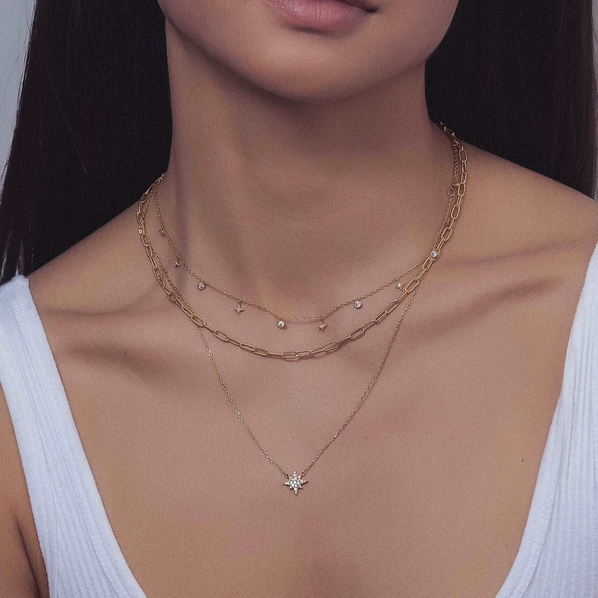 Gold vermeil layered chain trio with star and clear crystal charms, shown on a model's neck
