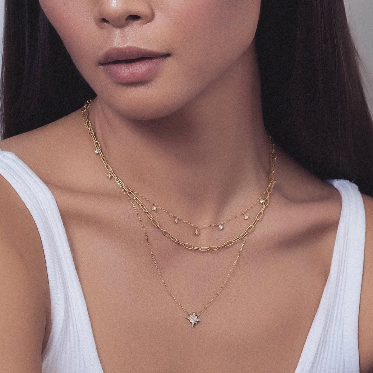 Gold vermeil star dangle necklace with white zirconia charms, shown layered on a model's neckline